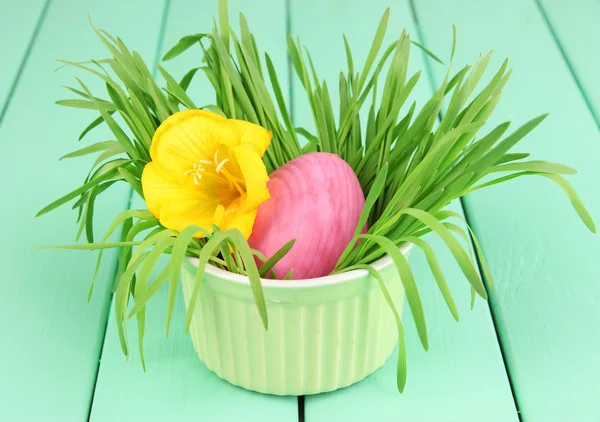 Huevo de Pascua en tazón con hierba sobre mesa de madera verde de cerca —  Fotos de Stock