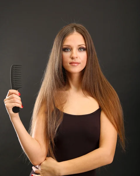 Portrait of beautiful woman brushing her hair on black background — Stock Photo, Image