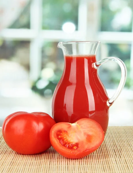 Tomato juice in pitcher on table on in room — Stock Photo, Image