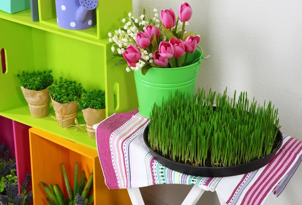 Scaffali colorati e tavolo con elementi decorativi e fiori — Foto Stock