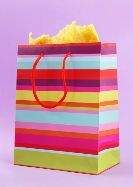 Striped shopping bag on purple background — Stock Photo, Image