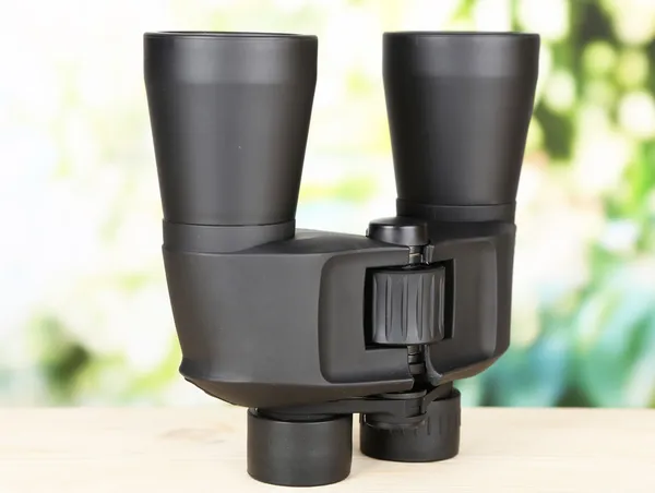 Černý moderní dalekohled na dřevěný stůl na zeleném pozadí — Stock fotografie