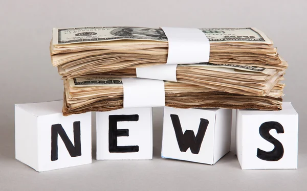 White paper cubes labeled "News" with money on grey background — Stock Photo, Image