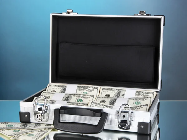 Resväska med 100 dollarsedlar på blå bakgrund — Stockfoto
