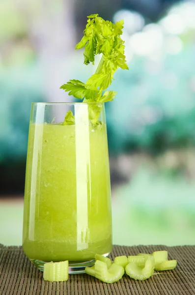 Glass of celery juice, on bamboo mat, on green background — Stock Photo, Image