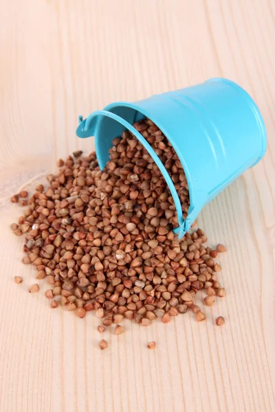 Overturned bucket with grains on wooden background — Stock Photo, Image