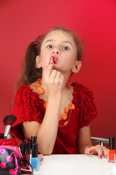 Lilla flickan i hennes mammas klänning, försöker måla läpparna — Stockfoto
