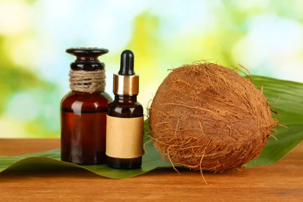 Kokosový olej v lahví s kokosy na zeleném pozadí — Stock fotografie