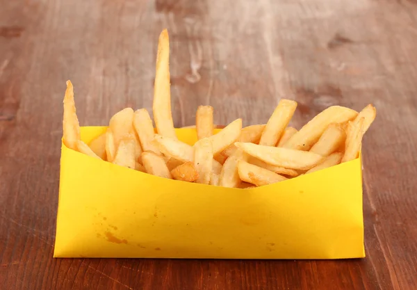 French fries in paper bag on wooden table close-up — Stock Photo, Image