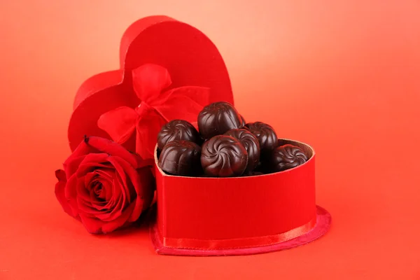 Dulces de chocolate en caja de regalo, sobre fondo rojo — Foto de Stock