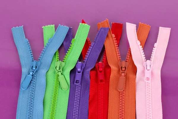 Multicolored zippers on purple background — Stock Photo, Image