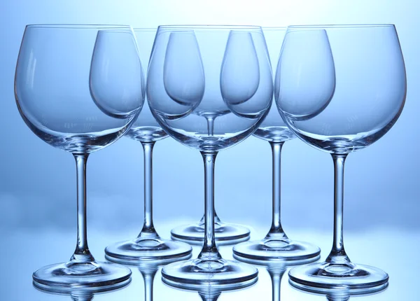 Lege wijnglazen gerangschikt op blauwe achtergrond — Stockfoto