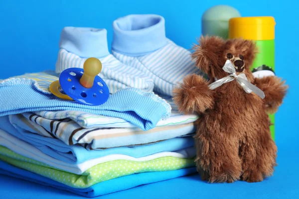 Pilha de roupas de bebê no fundo azul — Fotografia de Stock