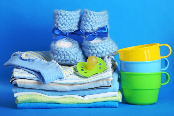 堆在蓝色背景上的婴儿衣服 — 图库照片
