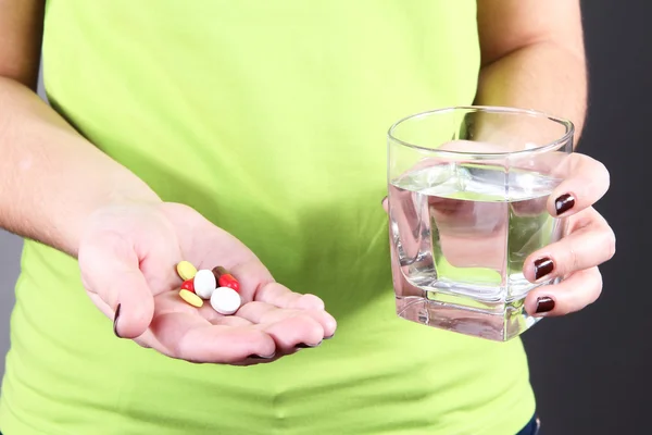 Muchas píldoras y agua de vidrio en la mano — Foto de Stock