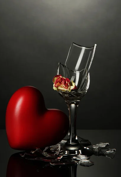 Rozbité sklenice na víno a srdce na šedém pozadí — Stock fotografie