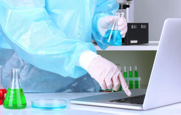 Scientist entering data on laptop computer with test tube close up — Stock Photo, Image