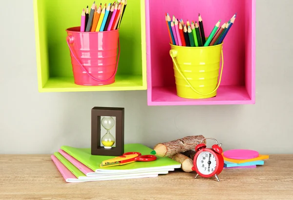 Lápis coloridos em pails em prateleiras no fundo bege Fotografia De Stock