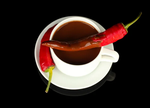 White cup with hot chocolate and chili pepper isolated on black Royalty Free Stock Photos