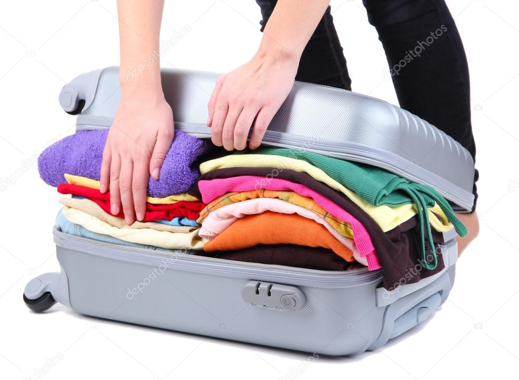 Girl tries to close the suitcase isolated on white
