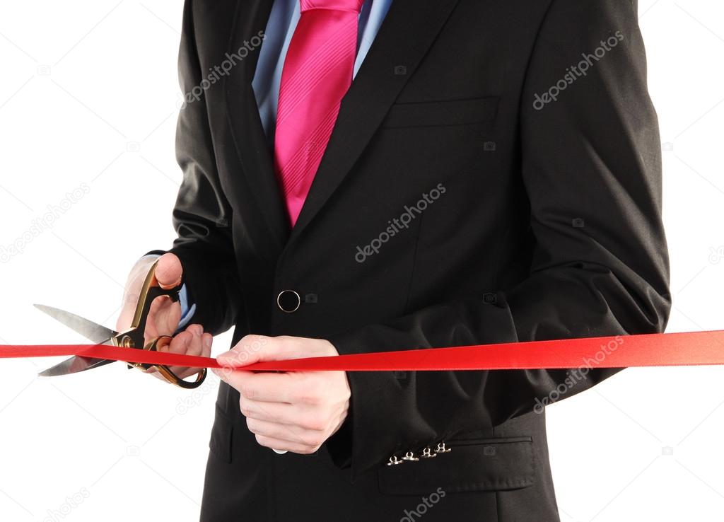 Man's hand cutting red ribbon with pair of scissors for ceremony isolated on white