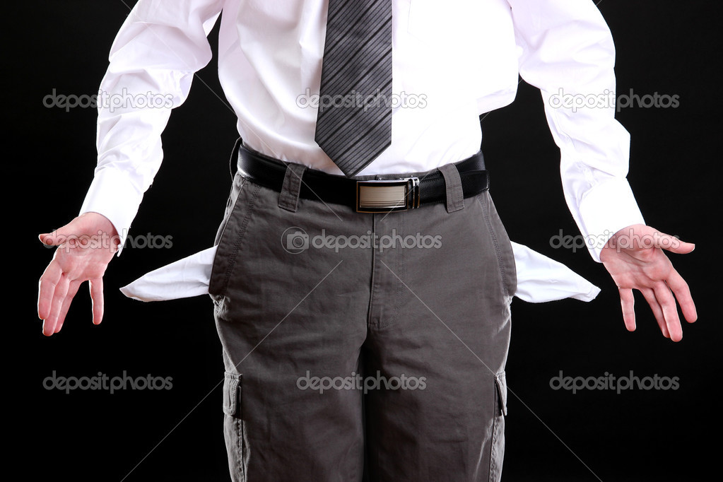 Business man showing his empty pockets, on black background