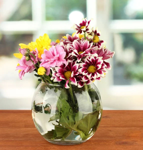 Colorful bouquet of chrysanthemums in a glass vase on wooden table close-up — Stock Photo, Image