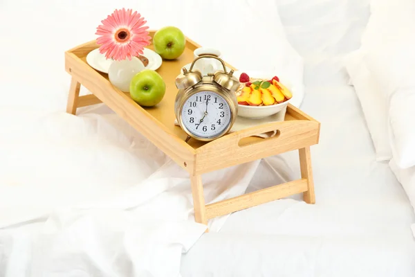 Houten dienblad met licht ontbijt op bed — Stockfoto