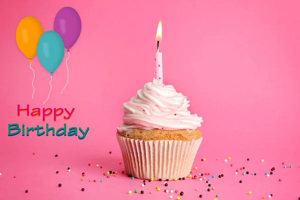 Cupcake de aniversário saboroso com vela, no fundo rosa — Fotografia de Stock