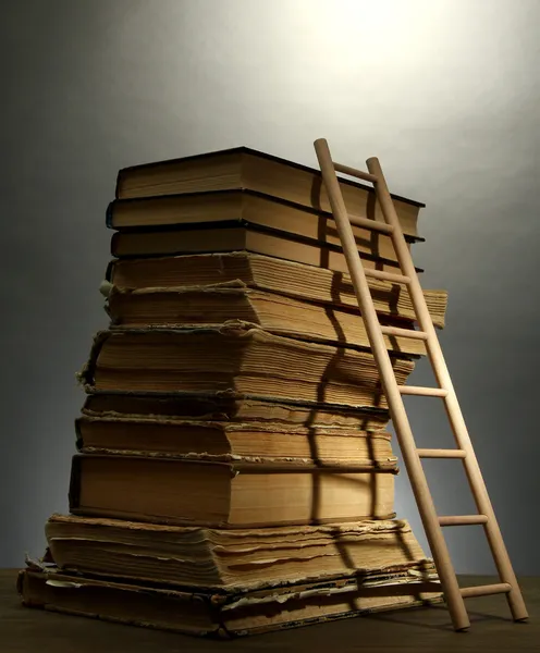 Old books and wooden ladder, on grey background — Stock Photo, Image