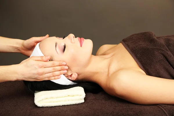 Hermosa joven en el salón de spa tomando masaje en la cabeza, sobre fondo oscuro — Foto de Stock