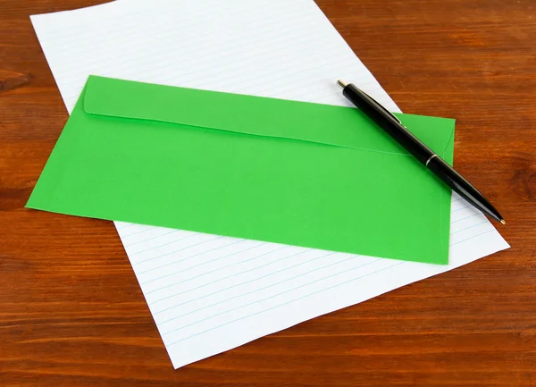 Kuvertet med penna och papper på trä bakgrund — Stockfoto