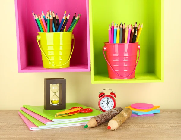 Lápices de colores en cubos en estantes sobre fondo beige — Foto de Stock