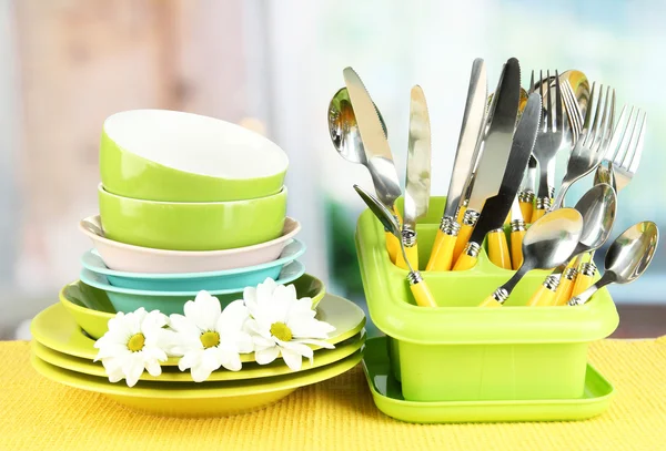 Tallrikar, gafflar, knivar, skedar och andra köksredskap på färg Servett, på ljus bakgrund — Stockfoto