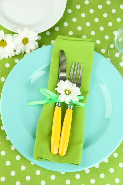 Couteau et fourchette enveloppés dans une serviette, sur une assiette, sur fond de nappe couleur — Photo