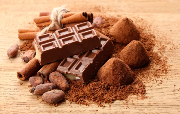 Состав шоколадных конфет, какао и специй на деревянном фоне — стоковое фото