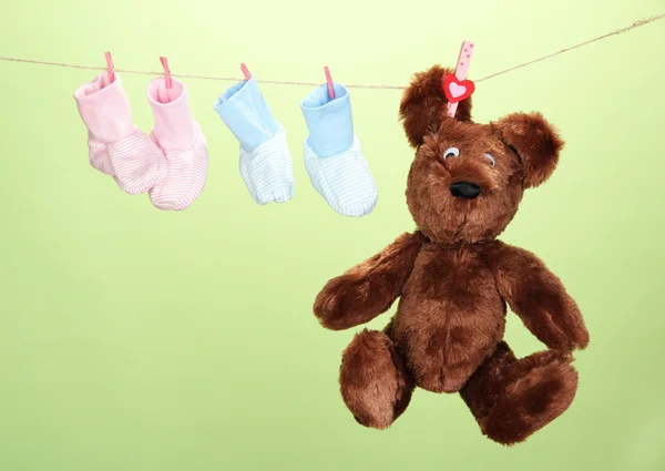 Baby booties hanging on clothesline, on color background — Stock Photo, Image