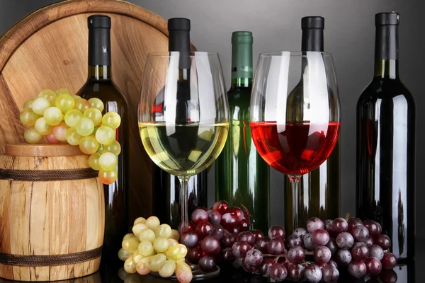 Ассортимент вина в стаканах и бутылках на сером фоне — стоковое фото