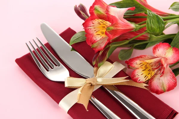 Tavolo da pranzo festivo con fiori su sfondo rosa — Foto Stock