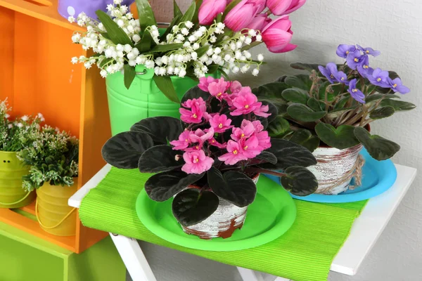 Prateleiras coloridas e mesa com elementos decorativos e flores — Fotografia de Stock