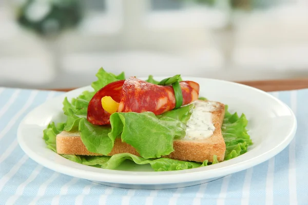 Salami rolls with paprika pieces inside, on roasted bread with cheese cream, on bright background — Stock Photo, Image