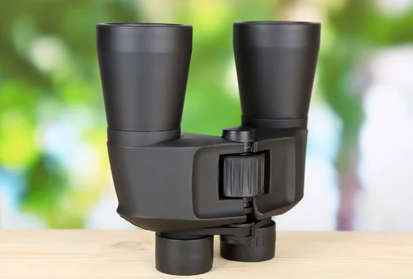 Černý moderní dalekohled na dřevěný stůl na zeleném pozadí — Stock fotografie