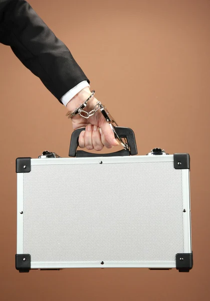 Hand with handcuff and suitcase, on color background — Stock Photo, Image