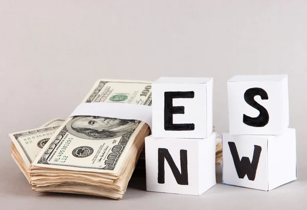 White paper cubes labeled "News" with money on grey background — Stock Photo, Image