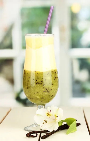 Delicious fruit smoothie on wooden table on window background — Stock Photo, Image