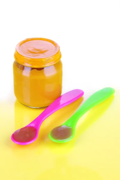 Comida para bebés con cucharas de destete sobre fondo amarillo —  Fotos de Stock