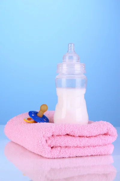 タオルと青色の背景にニップルのミルクのボトル — ストック写真