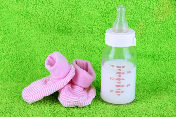 Bottle for milk and booties on towel background — Stock Photo, Image