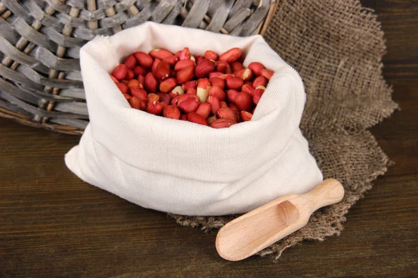 Peanuts in sack on wooden background — Stock Photo, Image
