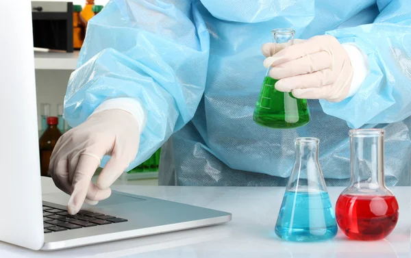 Scientist entering data on laptop computer with test tube close up — Stock Photo, Image
